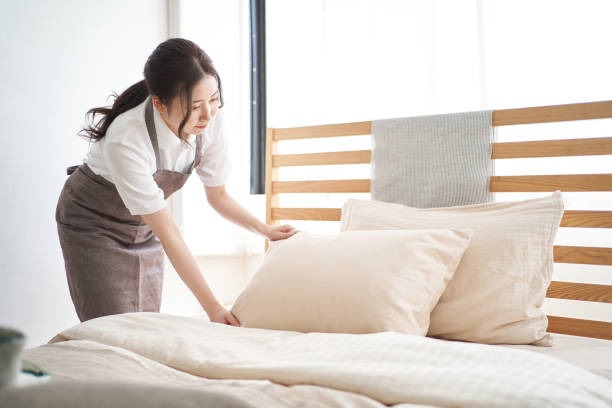 maid managing bed sheets in house